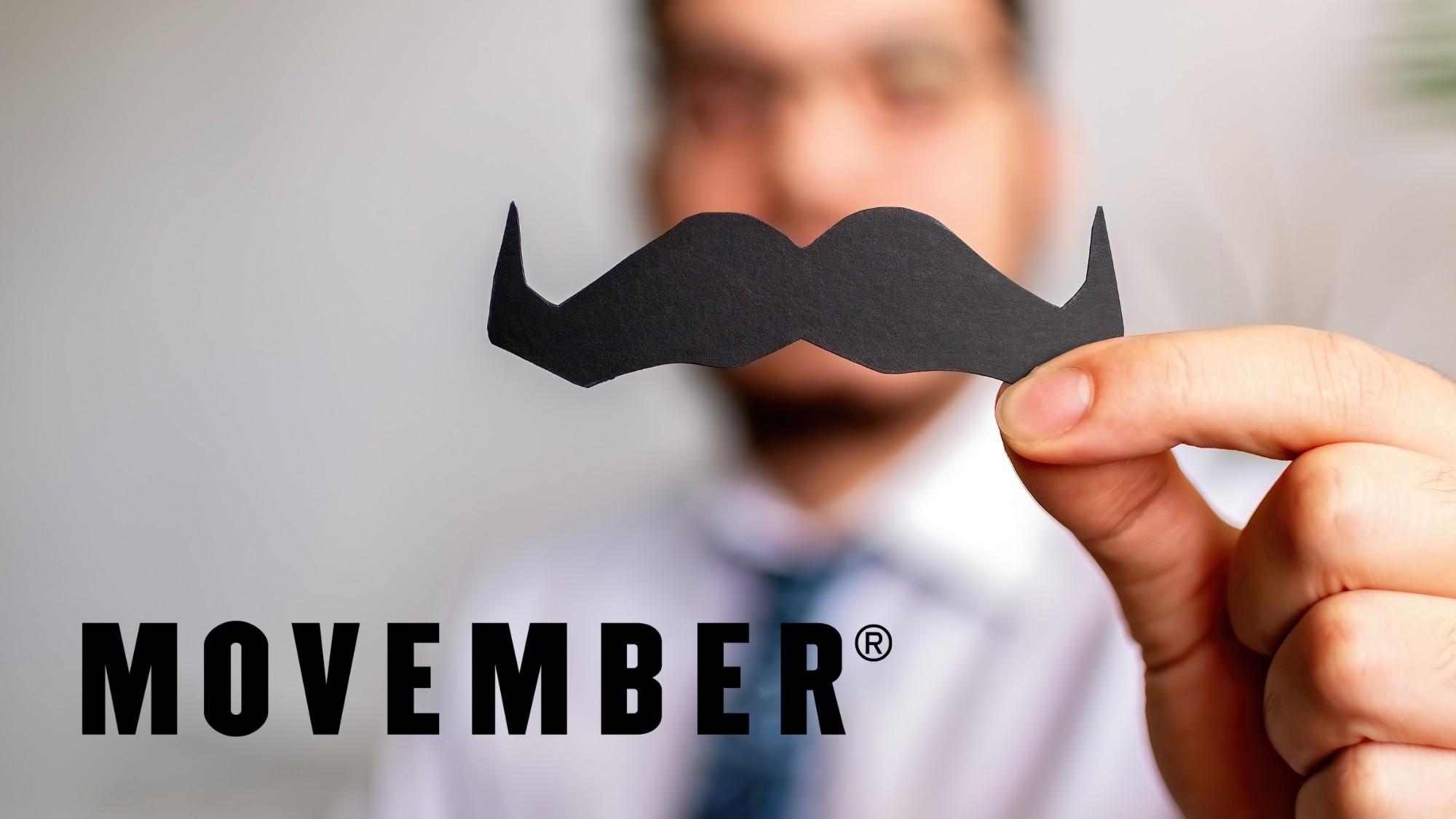 Blurred out man with a Movember moustache with the offical Movember logo